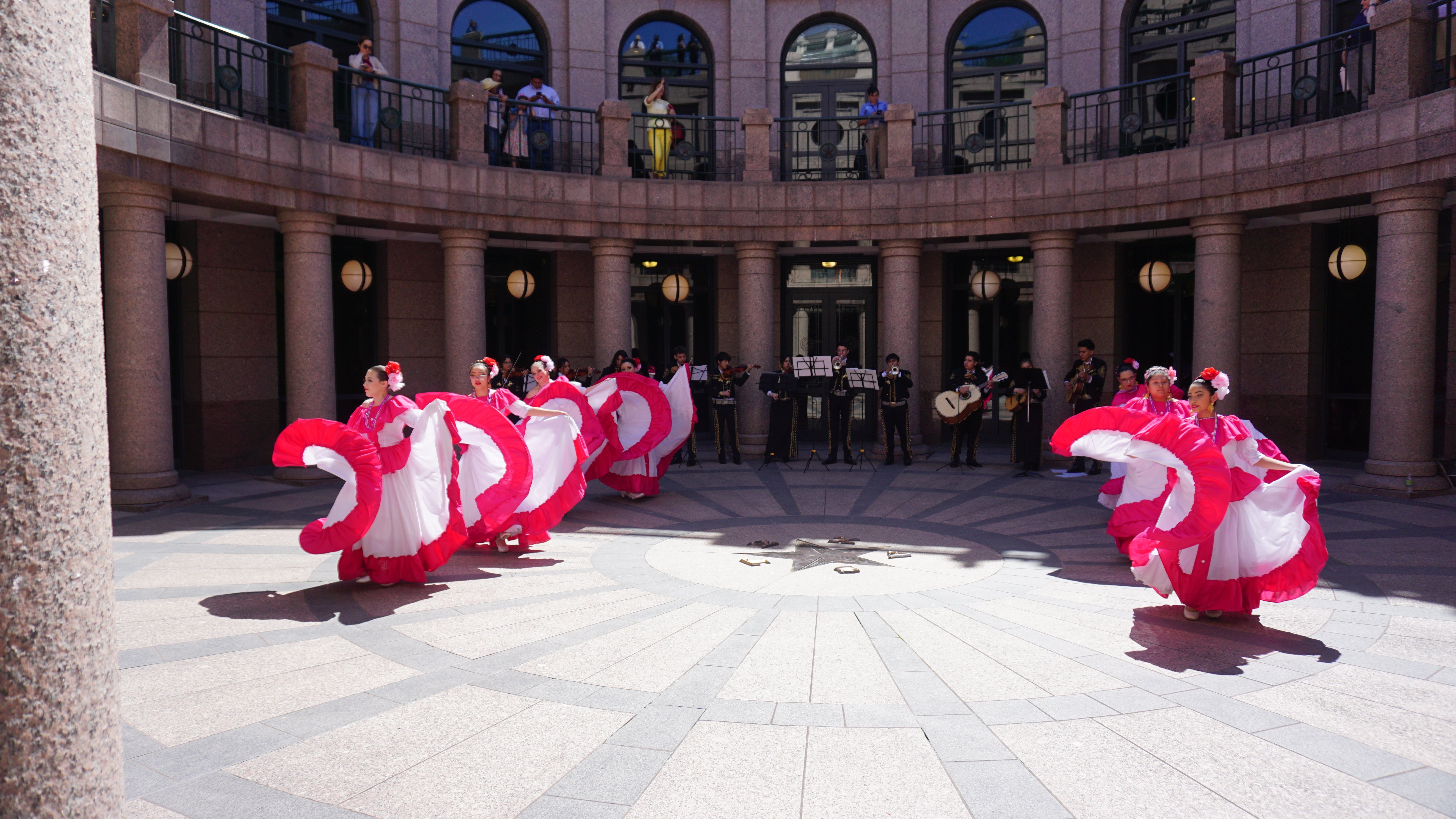 Mariachi performers and dancers in pink-white dresses at the Capitol