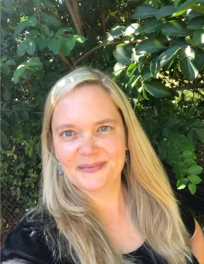 Headshot of Anita Swanson wearing a black t-shirt with a leafy background