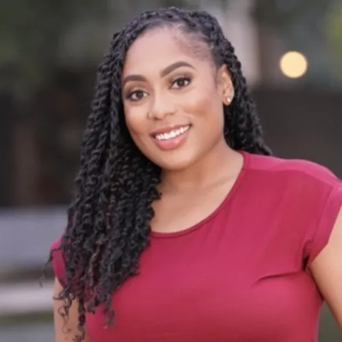 Description: Ashley is a young, African-American woman. She has natural, braided hair and wears a magenta colored shirt. 
