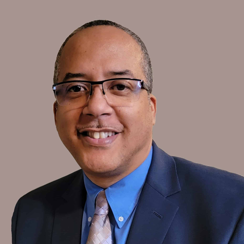 Sean Jackson Description: Sean is an African American man with short cropped hair and glasses. He wears a navy suit with a light blue shirt and a silver-patterned necktie.