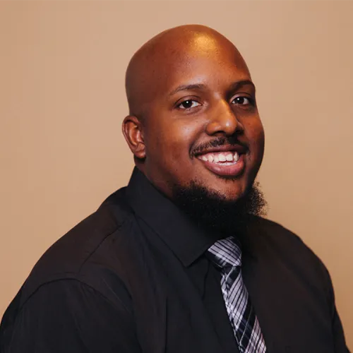 Earl is a young African American man with a bald head and a goatee. He wears a black shirt with a silver and black striped tie.