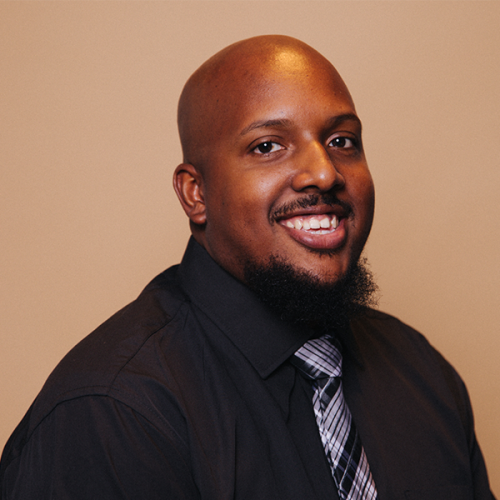 Earl is a young African American man with a bald head and a goatee. He wears a black shirt with a silver and black striped tie.