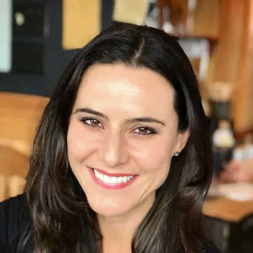 Portrait of Dr. Shari Ravenscroft, who has shoulder-length, dark brown hair and wears a black blouse with red lipstick.