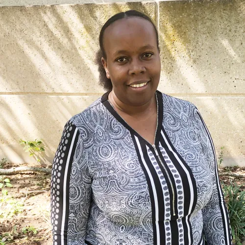 dark complexion, subtle smile and soft eyes. wearing a black and white floral blouse