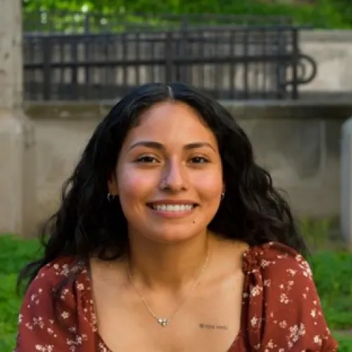 Ashley. Long, dark, curly hair with bright white smile and dark red top