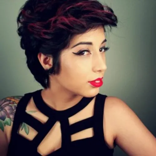 A person to the side, with short hair, with a flower tattoo, wearing a black shirt.