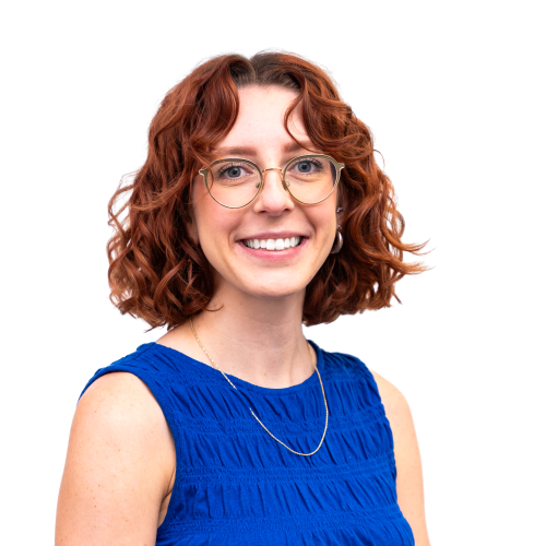 Caroline has short, curly red hair, glasses, and wears a blue top. 