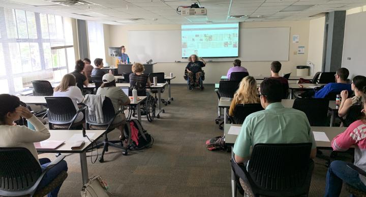 The November DASS Event with Stephanie Thomas at the head of a room discussing grassroots organizing and ADAPT. Students and staff watch her. 