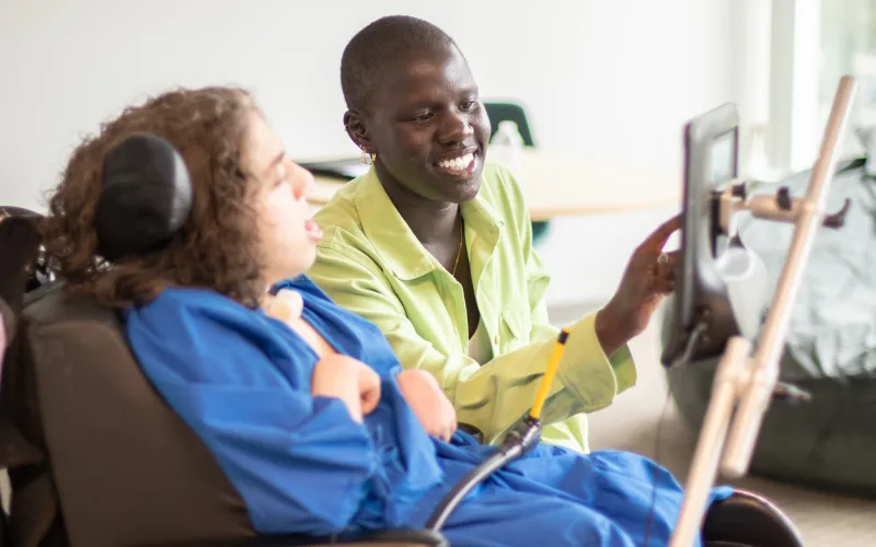 a therapist working on a tablet with a person in a wheelchair