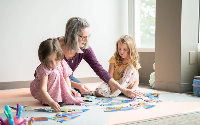 Family member with two children playing with a puzzle