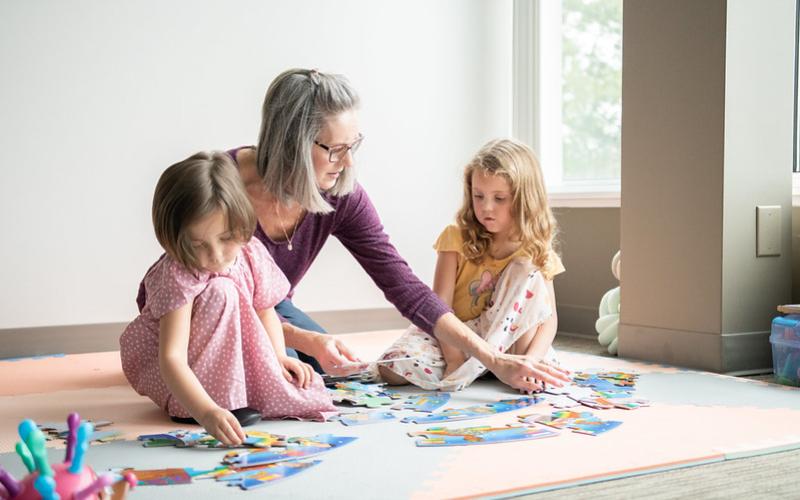 Family member with two children playing with a puzzle